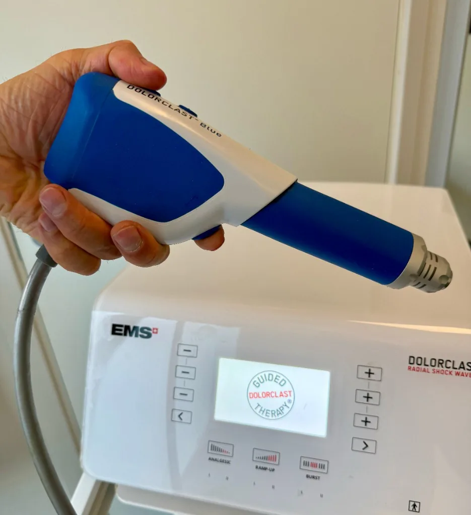 Håndstykket på EMS DolorClast Blue, med trykkbølgemaskinen i bakgrunnen